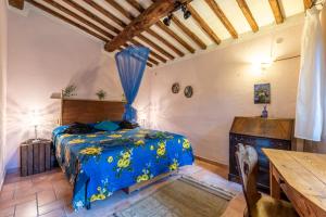 1 dormitorio con cama azul y mesa de madera en Paradis Oasis Santa Maria en Chiusdino