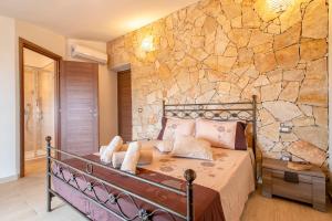 a bed in a room with a stone wall at Villa Felicità in Sorso