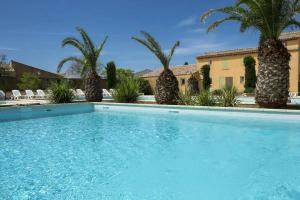 uma piscina com palmeiras e um edifício em Le Mazet de Leon em Arles