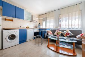 a kitchen with blue cabinets and a couch and a table at A 100m de la Playa Salou in Salou
