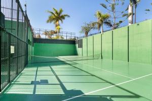 a tennis court with palm trees in the background at Isabel Home For Families in San Bartolomé de Tirajana