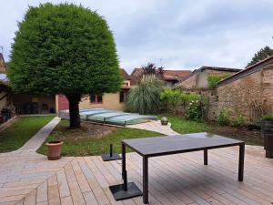 a table in the middle of a courtyard with a tree at Maison avec piscine in Marciac