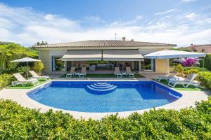 Bellviure Luxury Villa في Marratxí : فيلا مع مسبح وكراسي ومظلات