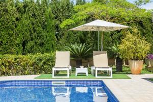 duas cadeiras e um guarda-sol junto a uma piscina em Bellviure Luxury Villa em Marratxí 