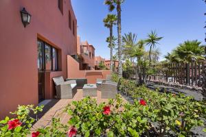 een patio met stoelen en bloemen voor een huis bij Casa Desierto Azul in Corralejo