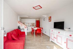 Una sala de estar con un sofá rojo y una cocina. en Gufo di Mare - Rosso, en Savelletri di Fasano