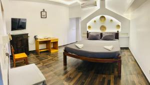 a bedroom with a bed and a desk and a television at The French Villa Elite in Puducherry