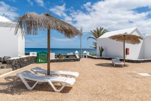 un patio con 2 sillas y una sombrilla y el océano en Bungalow Alma Ocean View, en Puerto del Carmen