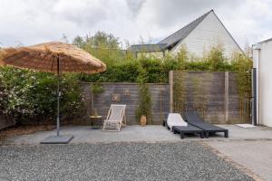 um pátio com um guarda-sol, cadeiras e um baloiço em Villa West Attitude em Erdeven