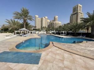 a swimming pool in a resort with buildings in the background at Al Hamra golf & sea resort lagoon view suite in Ras al Khaimah