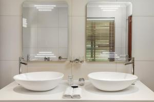 Aaldering Luxury Lodges في ستيلينبوش: حمام مع مغسلتين بيضاء على منضدة