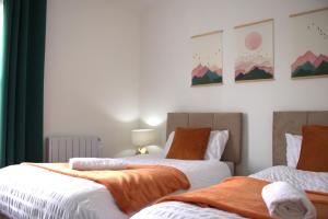 a bedroom with two beds with orange and white sheets at Top Spot 2-Bed Spacious Apartment Town Centre Train Station WIFI in Colchester