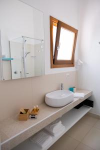 La salle de bains blanche est pourvue d'un lavabo et d'un miroir. dans l'établissement Baglio La Riserva, à Scopello