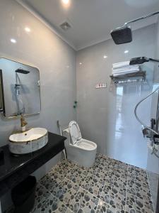 uma casa de banho com um lavatório, um WC e um espelho. em Royal Homestay - Royal Center em Móng Cái