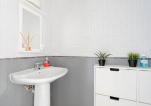 ein Badezimmer mit einem weißen Waschbecken und einem weißen Schrank in der Unterkunft Kitesurf HQ - 3 Bed Luxury Townhouse with Ocean Views in Corralejo + 19 Fotos