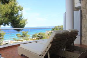 una sedia su un balcone con vista sull'oceano di Amelia Apartments a Kallithea