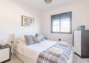 ein weißes Schlafzimmer mit einem Bett und einem Fenster in der Unterkunft Kitesurf HQ - 3 Bed Luxury Townhouse with Ocean Views in Corralejo