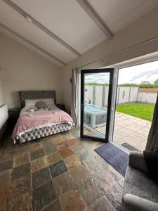 um quarto com uma cama e uma porta de vidro deslizante em Dwylig Isa Holiday Cottages em Rhuddlan