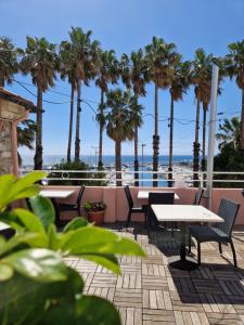 a patio with tables and chairs and palm trees at Vela Bianca H & R in Diano Marina