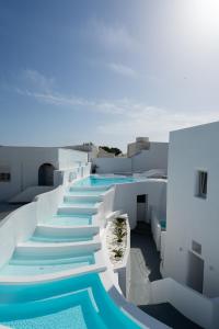 - une vue aride sur un bâtiment avec des escaliers bleus et blancs dans l'établissement White Concept Caves, à Fira
