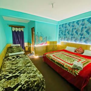 two beds in a room with blue walls at Madana Inn Manali in Manāli