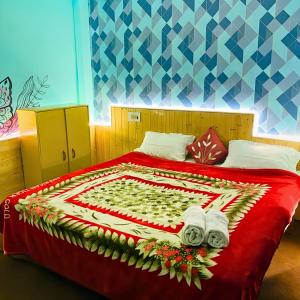 a bedroom with a bed with a red blanket and towels at Madana Inn Manali in Manāli