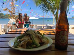 a plate of food on a table next to a bottle of beer at Zhaya's Beach & Cottages in El Nido