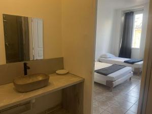 uma casa de banho com um lavatório, um espelho e 2 camas em Hotel Du Centre em Marselha