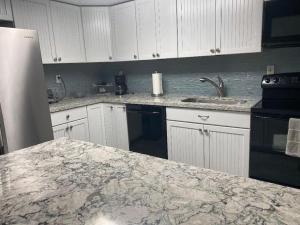 a kitchen with white cabinets and a marble counter top at Oceanfront retreat, serene views & screened lanai #30 in Marathon