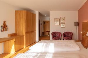 ein Schlafzimmer mit einem Bett und zwei roten Stühlen in der Unterkunft Buchberg38 in Buchberg bei Herberstein