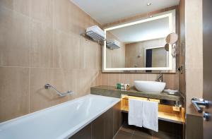 uma casa de banho com uma banheira, um lavatório e um espelho. em Hilton London Tower Bridge em Londres