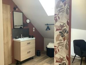 a bathroom with a sink and a staircase with a mirror at La Flânerie in Widehem