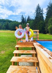 two people standing on a dock next to a swimming pool at Olza Karczma i pokoje in Istebna