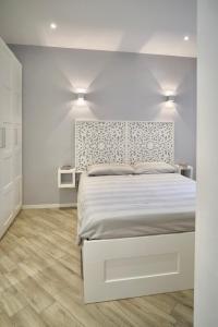 a white bedroom with a bed and two lights at Villa Pietrantoni in Tivoli