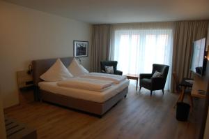 ein Schlafzimmer mit einem Bett, zwei Stühlen und einem Fernseher in der Unterkunft Altstadthotel Millipp in Beilngries