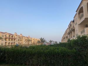 a row of apartment buildings with palm trees and bushes at Laserina Palm Beach for families only ground floor with big garden in Ain Sokhna