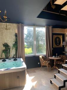 een badkamer met een bad, een tafel en een raam bij Chambres d'hôtes La Mascrabiere BED & SPA in Albi