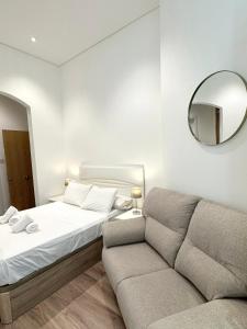 1 dormitorio con cama, sofá y espejo en Delightful City Centre Studio Clarendon Apartment - Grand Central House en Gibraltar