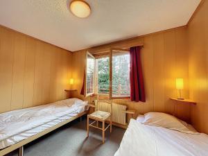 two beds in a room with a window at Pâquerette 1er in Verbier