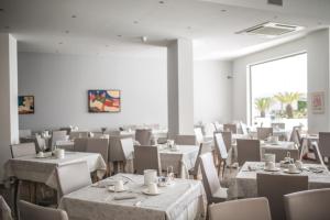 a dining room with white tables and chairs at Hotel Bellavista in Lignano Sabbiadoro