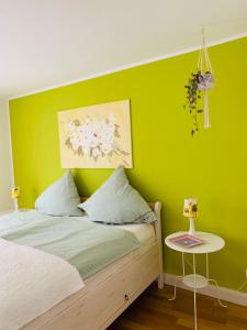 ein grünes Schlafzimmer mit einem Bett und einem Tisch in der Unterkunft Casa Cinzia Sara in Eckernförde