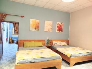 2 Betten in einem Zimmer mit Gemälden an der Wand in der Unterkunft Nhat Ha Homestay in Vũng Tàu + 12 Fotos