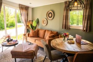 a living room with a couch and a table at Luxe Chalet vakantiepark Meerwijck, vlakbij Groningen in Kropswolde