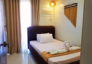 Un dormitorio con una cama con una toalla. en Affordable Summer Homes with FREE Pool, Gym and Parking near Puerto Princesa Palawan Airport -T21Kunzite, en Puerto Princesa City