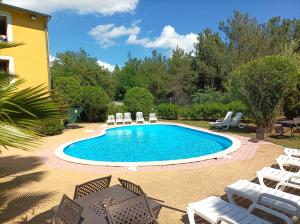 a swimming pool with chairs and a table at Cit'Hotel Hotel Prime - Montpelier Ouest -Saint Jean de Vedas in Saint-Jean-de-Védas