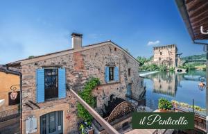 an old building next to a river with a castle at Il Borghetto Vacanze nei Mulini in Valeggio sul Mincio