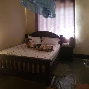 Cama pequeña en habitación con ventana en Safari Junction Backpackers hostel, en Iringa