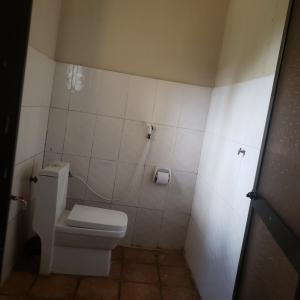 a bathroom with a toilet and a tiled wall at Safari Junction Backpackers hostel in Iringa
