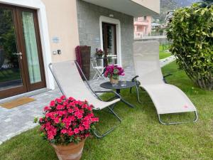 two chairs and a table and flowers on a yard at CASA VACANZE LA BRENTA in Chiavenna
