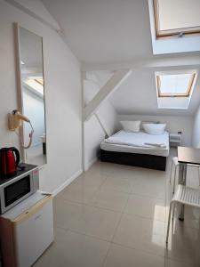 a small white room with a bed and a table at Apartamenty Hoża Attic Studio in Warsaw
